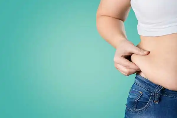 Image of woman pinching her love handles to show weight gain Maryhill