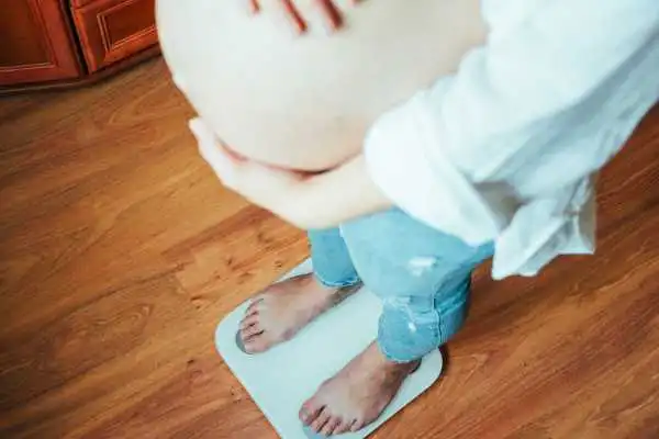 Image of woman weighing herself and experiencing weight gain through pregnancy Maryhill