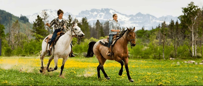 Confident plus-size woman riding Maryhill a horse through a field with a smile on her face.
